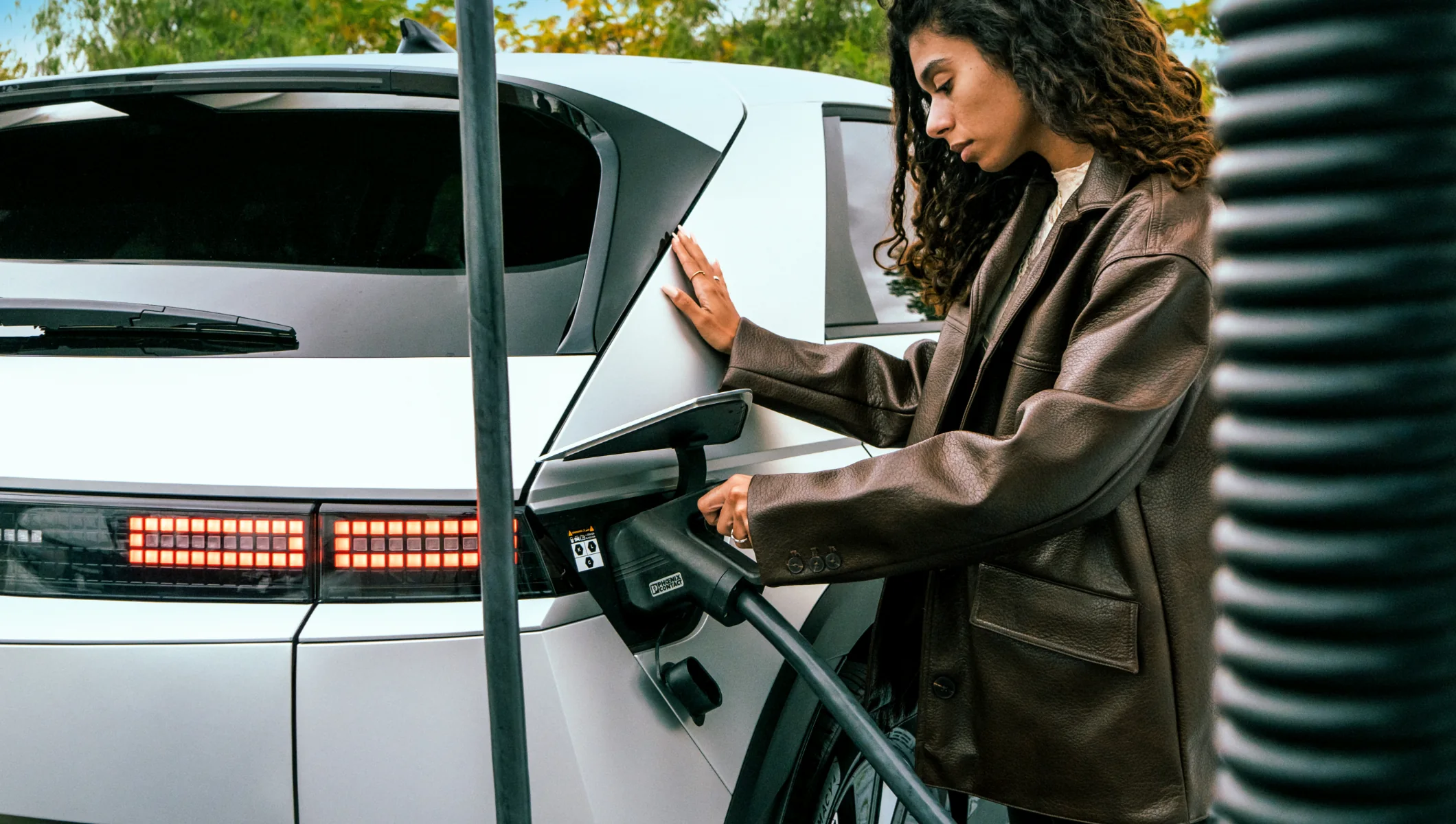 mulher a colocar manipulo a carregar carro elétrico