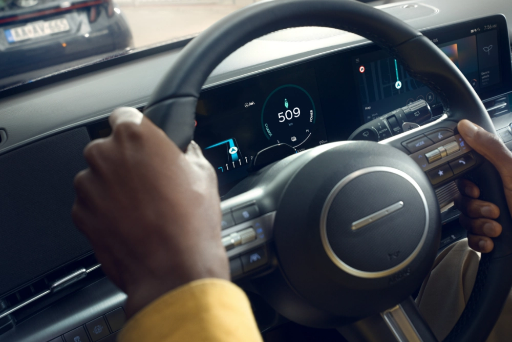 	Condutor ao volante de carro elétrico Hyundai com painel digital a indicar 509 km de autonomia.